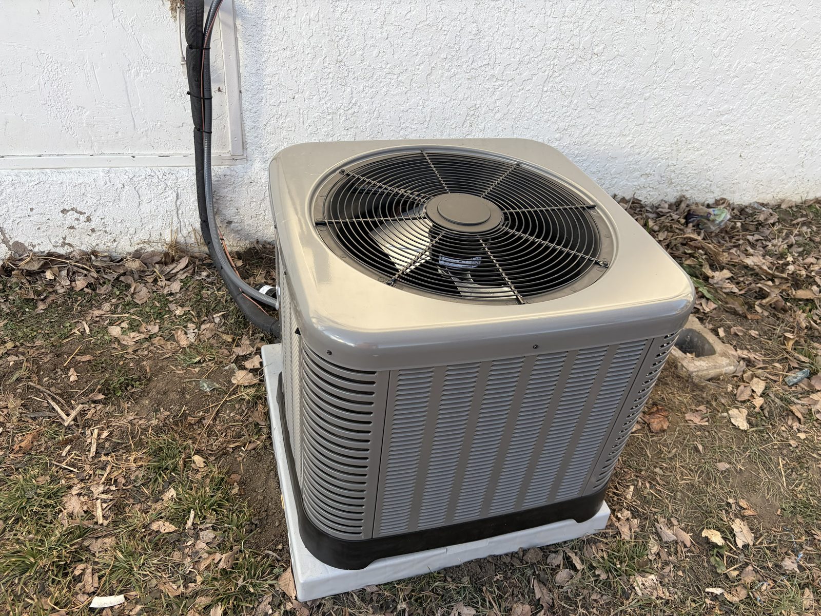 Outdoor air conditioning condenser unit beside a home's exterior wall